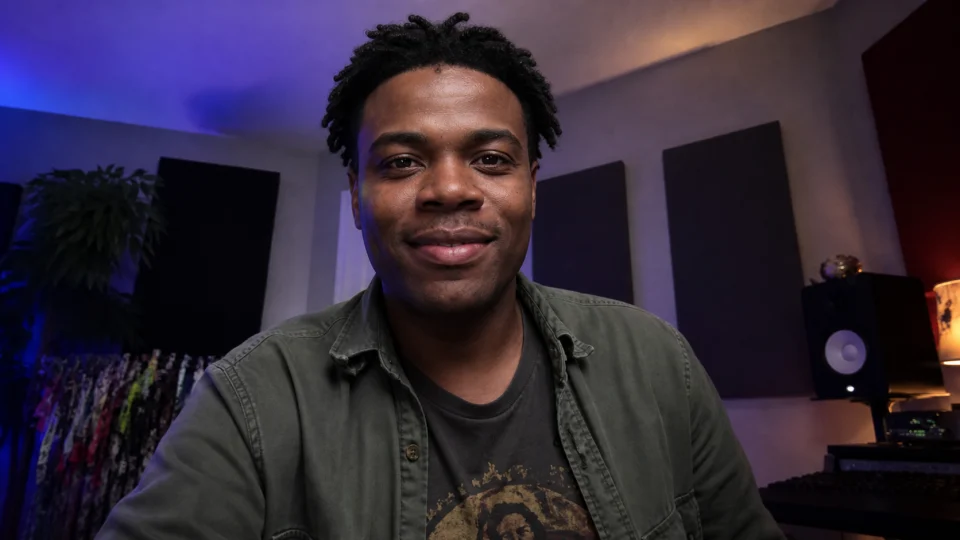 A venue marketer smiling toward his webcam from a home music studio
